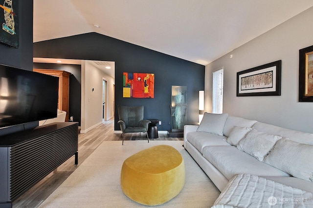 living area featuring lofted ceiling, wood finished floors, and baseboards