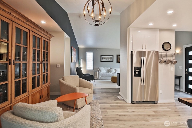 interior space featuring baseboards, white cabinets, hanging light fixtures, stainless steel refrigerator with ice dispenser, and light wood finished floors