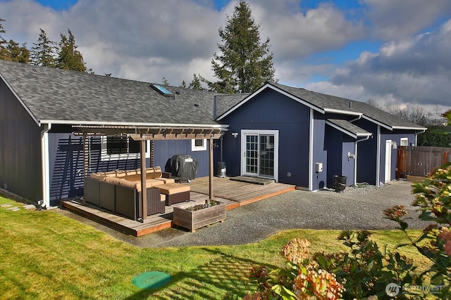 rear view of property with a shingled roof, an outdoor hangout area, fence, a deck, and a yard