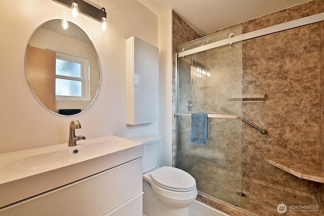 bathroom with a stall shower, vanity, and toilet