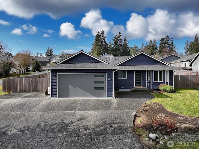 ranch-style home featuring a garage, a shingled roof, fence, concrete driveway, and a front lawn