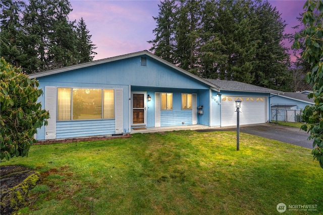 ranch-style home featuring a garage, driveway, and a front lawn