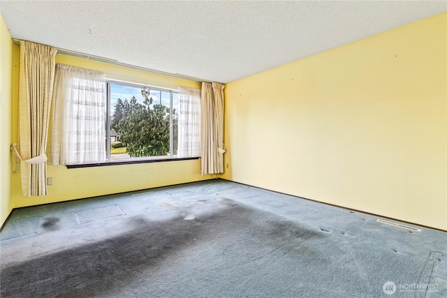 carpeted empty room with visible vents and a textured ceiling