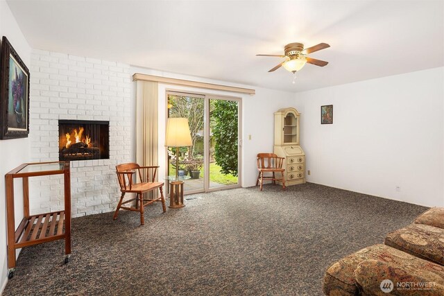 sitting room with carpet, a fireplace, and a ceiling fan