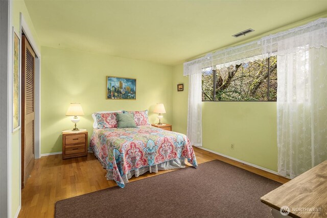 bedroom featuring a closet, wood finished floors, visible vents, and baseboards