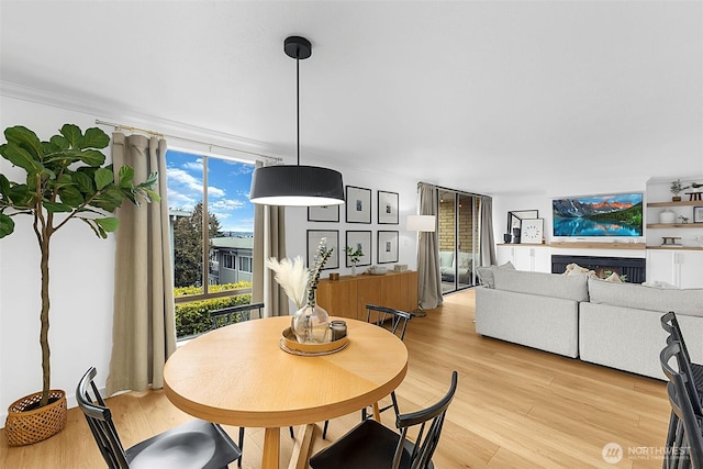 dining room featuring light wood-type flooring, crown molding, and expansive windows