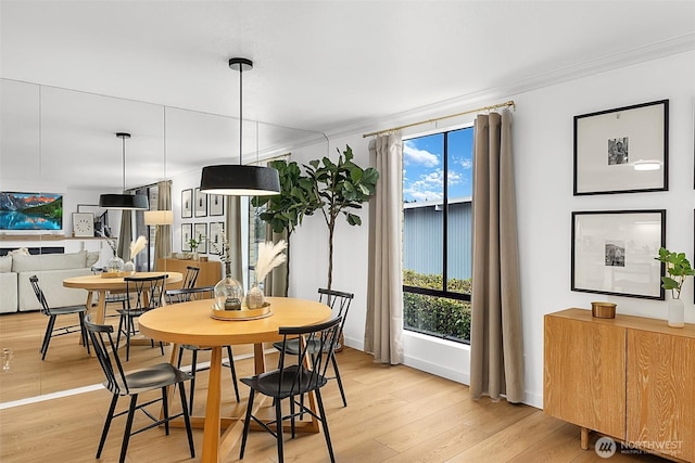 dining area featuring ornamental molding, light hardwood / wood-style floors, and a healthy amount of sunlight