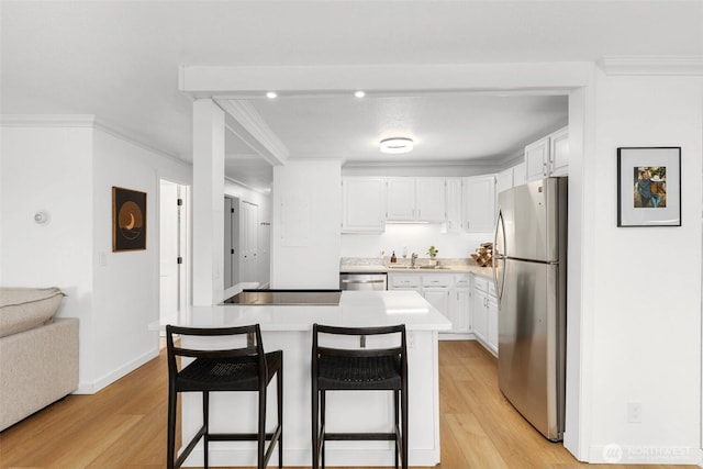 kitchen featuring white cabinetry, appliances with stainless steel finishes, crown molding, and a kitchen breakfast bar