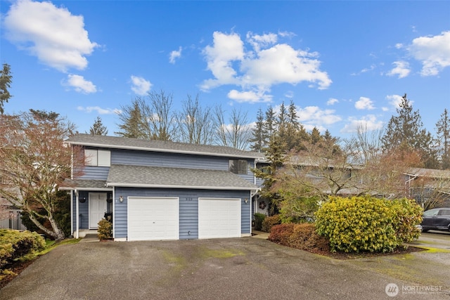 traditional-style home with an attached garage, a shingled roof, and aphalt driveway