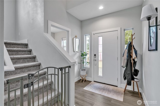 foyer entrance featuring stairs, baseboards, wood finished floors, and recessed lighting