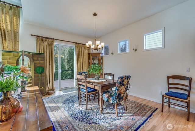 dining space featuring an inviting chandelier, baseboards, and wood finished floors