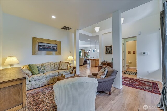 living area with light wood-style flooring, visible vents, baseboards, and recessed lighting