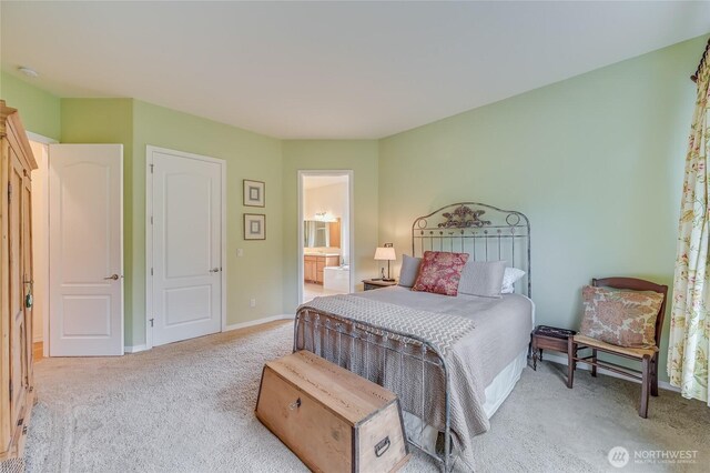 bedroom with baseboards, ensuite bath, and light colored carpet