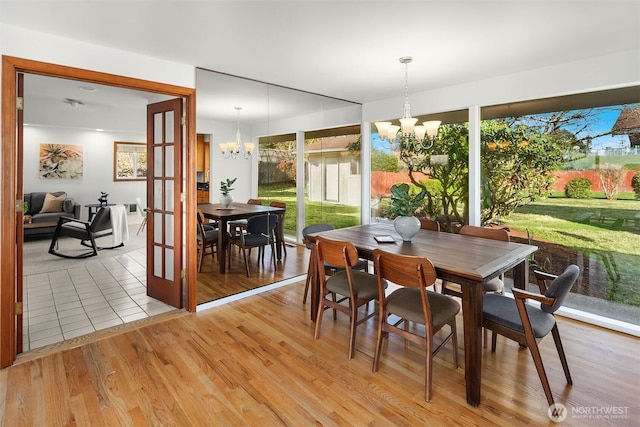 dining room featuring light wood-type flooring, french doors, and an inviting chandelier