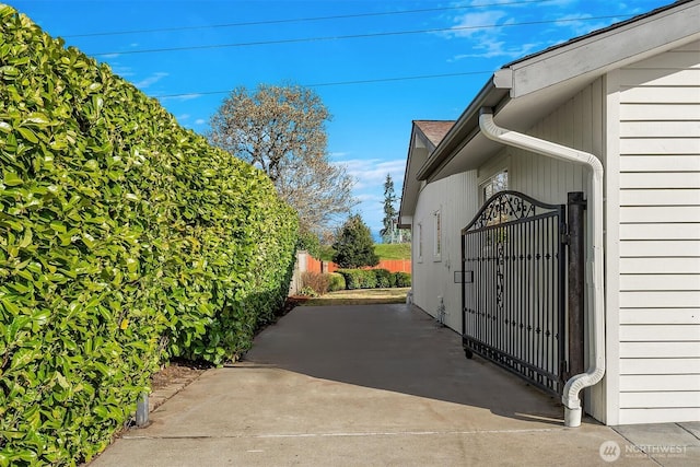 view of side of home featuring fence and a gate