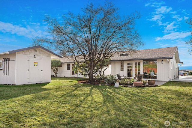 rear view of house with a storage unit, an outdoor structure, french doors, and a yard