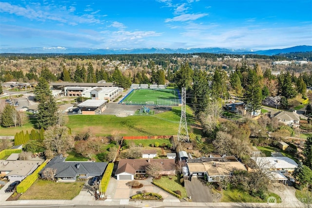 drone / aerial view featuring a residential view, a mountain view, and a wooded view