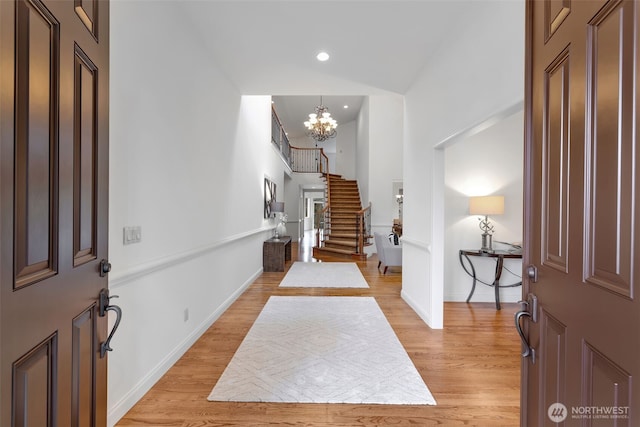 entryway featuring light wood-style flooring, a chandelier, stairway, and baseboards