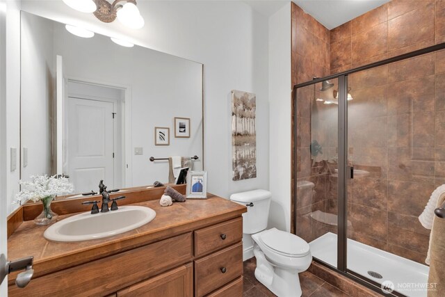 bathroom with toilet, tile patterned flooring, a shower stall, and vanity