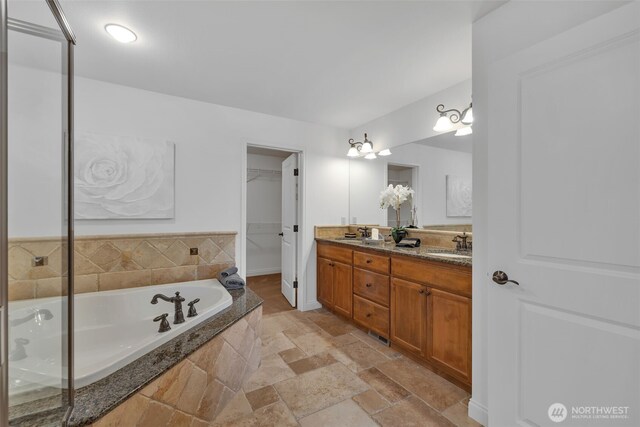 full bathroom with a garden tub, double vanity, a sink, and stone tile flooring