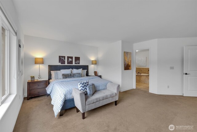 bedroom featuring baseboards, ensuite bath, and light colored carpet