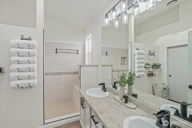 bathroom featuring tiled shower, lofted ceiling, and vanity