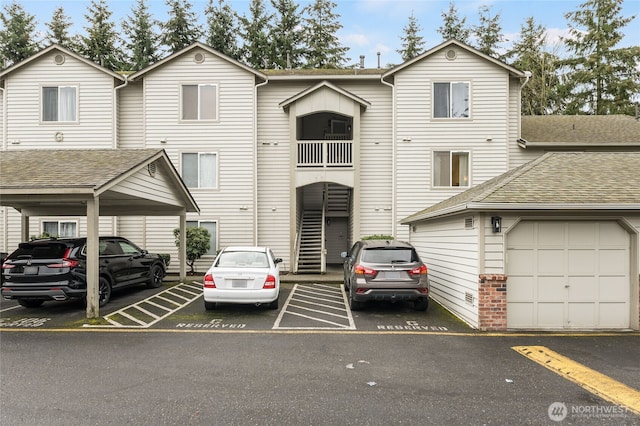 multi unit property featuring uncovered parking, brick siding, and a shingled roof