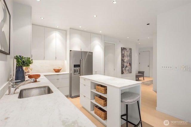 kitchen featuring white cabinetry, high quality fridge, a sink, and open shelves