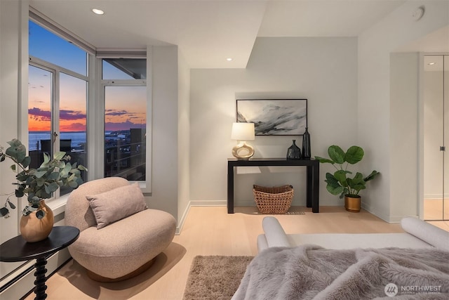 living area with baseboards, wood finished floors, and recessed lighting