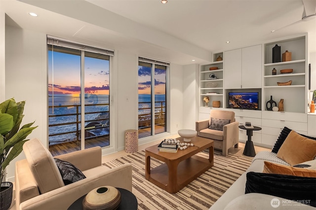 living room with built in shelves, recessed lighting, a water view, and expansive windows