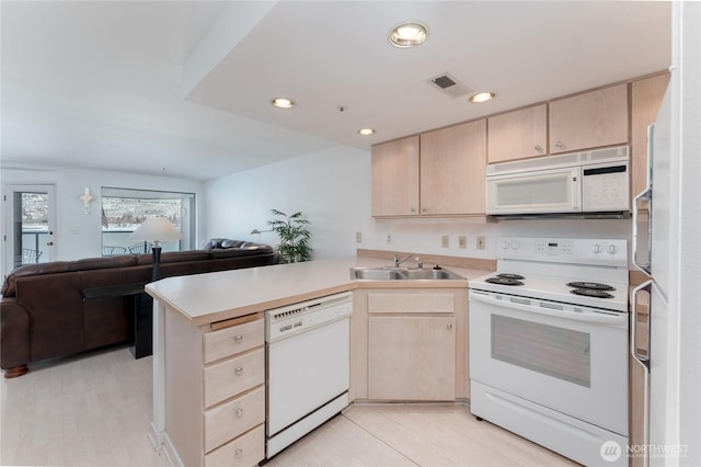 kitchen with sink, white appliances, light brown cabinetry, and kitchen peninsula