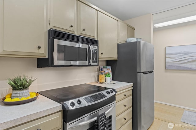 kitchen featuring appliances with stainless steel finishes, cream cabinetry, and light hardwood / wood-style flooring