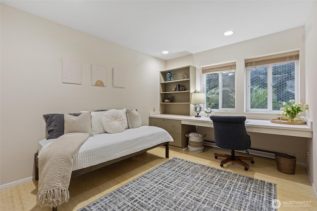 home office with light hardwood / wood-style flooring, built in desk, and a baseboard radiator