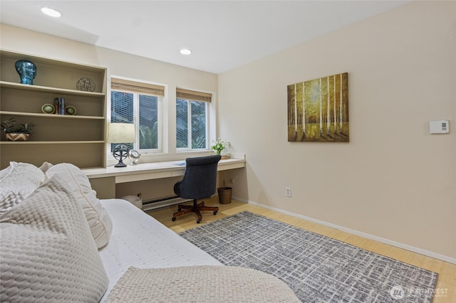 bedroom with built in desk and hardwood / wood-style floors