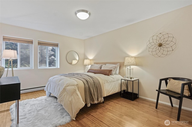 bedroom with baseboard heating and light hardwood / wood-style flooring