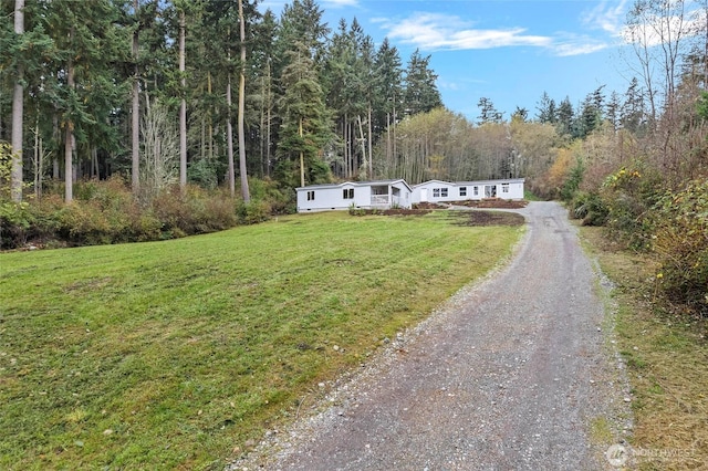 view of front of home with driveway, a front lawn, and a wooded view