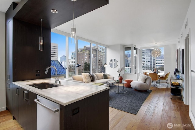 kitchen featuring a view of city, light countertops, hanging light fixtures, a sink, and dishwasher