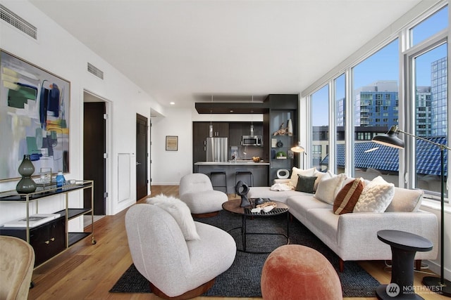 living room with light wood-style floors, baseboards, visible vents, and a city view