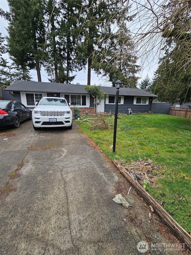 ranch-style house with a front lawn, fence, and aphalt driveway