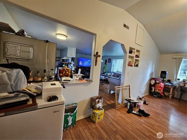 kitchen featuring open floor plan, visible vents, vaulted ceiling, and wood finished floors