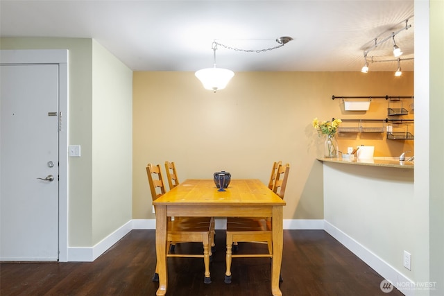 dining room featuring rail lighting, baseboards, and wood finished floors