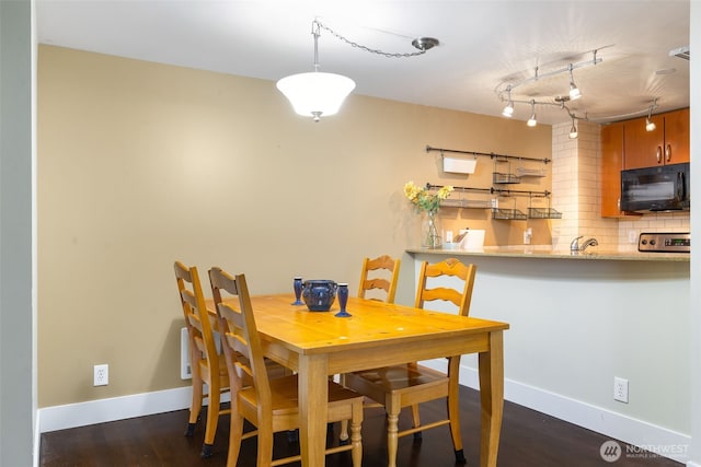 dining area with rail lighting, baseboards, and dark wood-type flooring