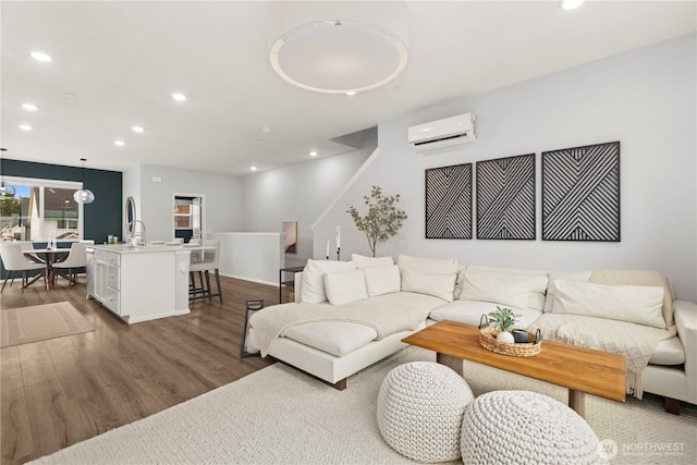 living room with recessed lighting, a wall mounted air conditioner, and wood finished floors