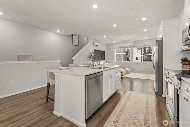 kitchen featuring stainless steel appliances, a sink, white cabinetry, light countertops, and a center island with sink