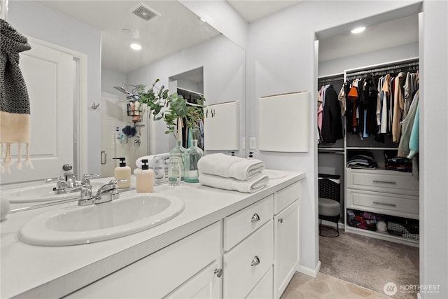 bathroom with vanity, a walk in closet, visible vents, and a shower stall