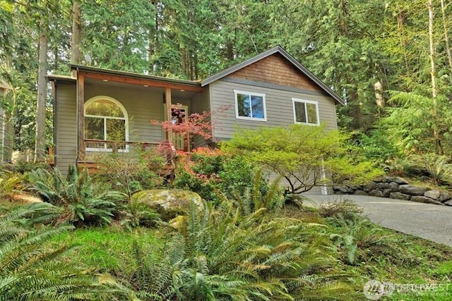 view of front of property featuring an attached garage, a forest view, and concrete driveway