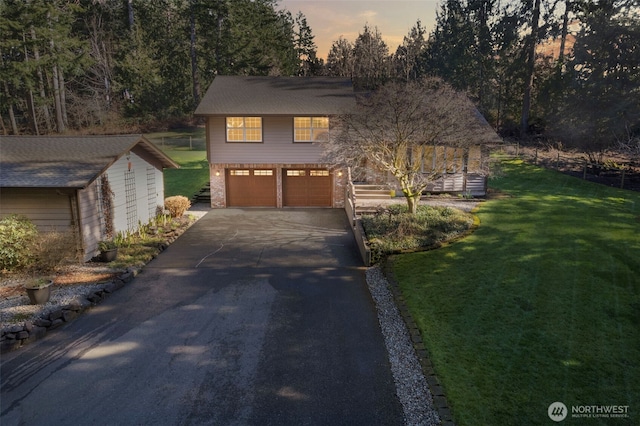 view of front of home with aphalt driveway, a front lawn, an attached garage, and brick siding