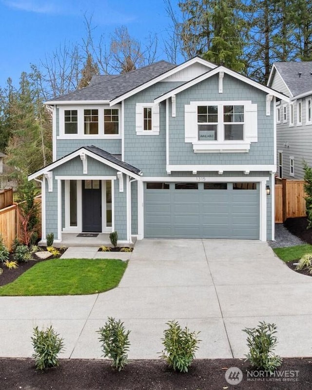 view of front of property featuring an attached garage, concrete driveway, and fence