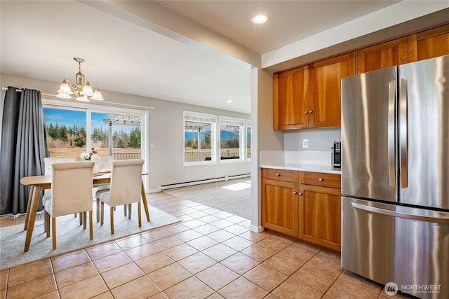 kitchen with hanging light fixtures, stainless steel refrigerator, a notable chandelier, baseboard heating, and light tile patterned floors