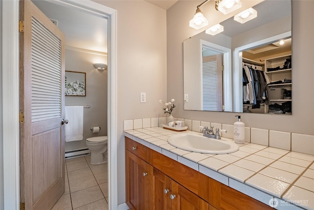 bathroom with tile patterned flooring, vanity, toilet, and a baseboard heating unit